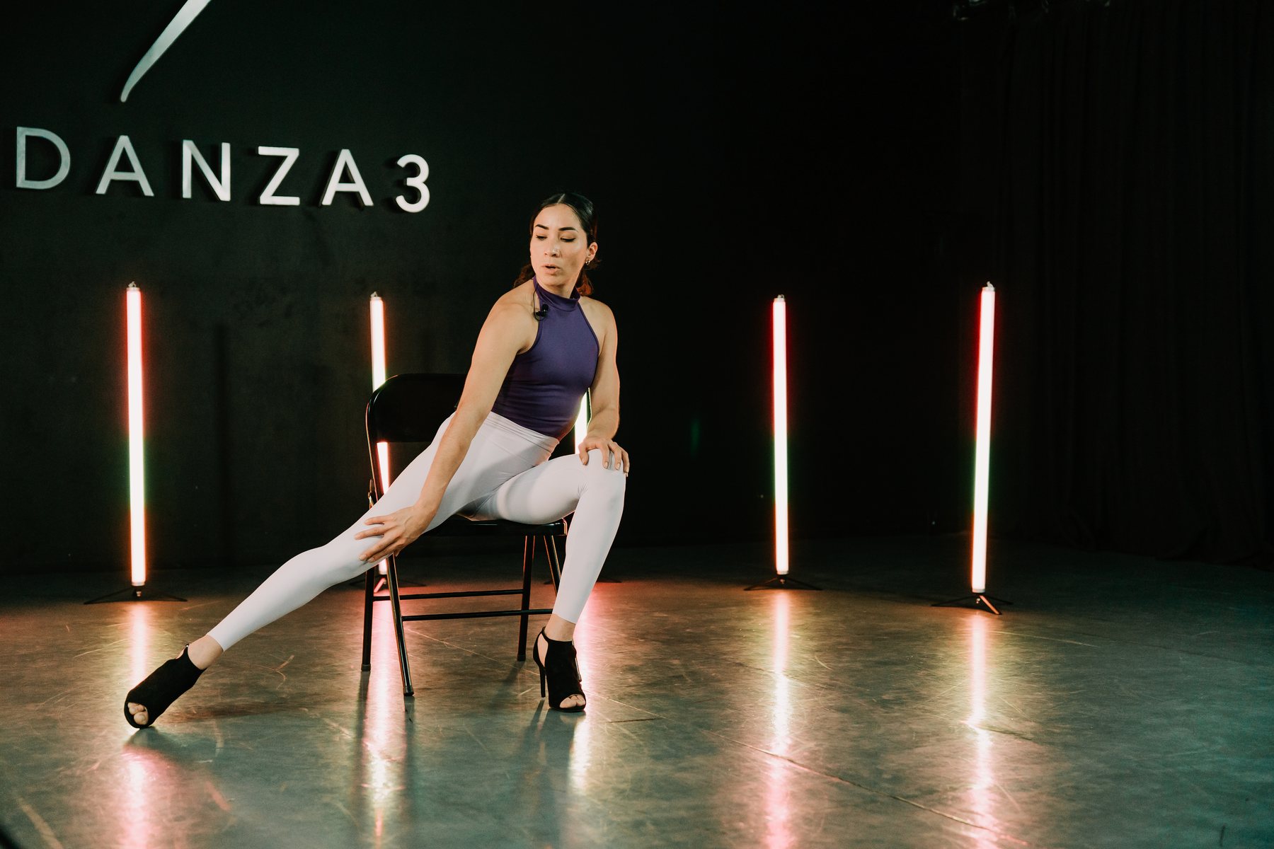 Mujer sentada en movimiento libre bajo luces de escenario